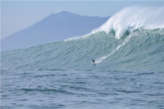Stephane Iralour en train de surfer la vague de Belharra avec la montagne de la Rhune en arrière-plan. Photo Greg Rabejac