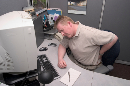 homme au travail devant un ordinateur souffrant de mal de dos - lombalgie - douleurs - stress - TMS - troubles musculo-squelettiques - iStockphoto
